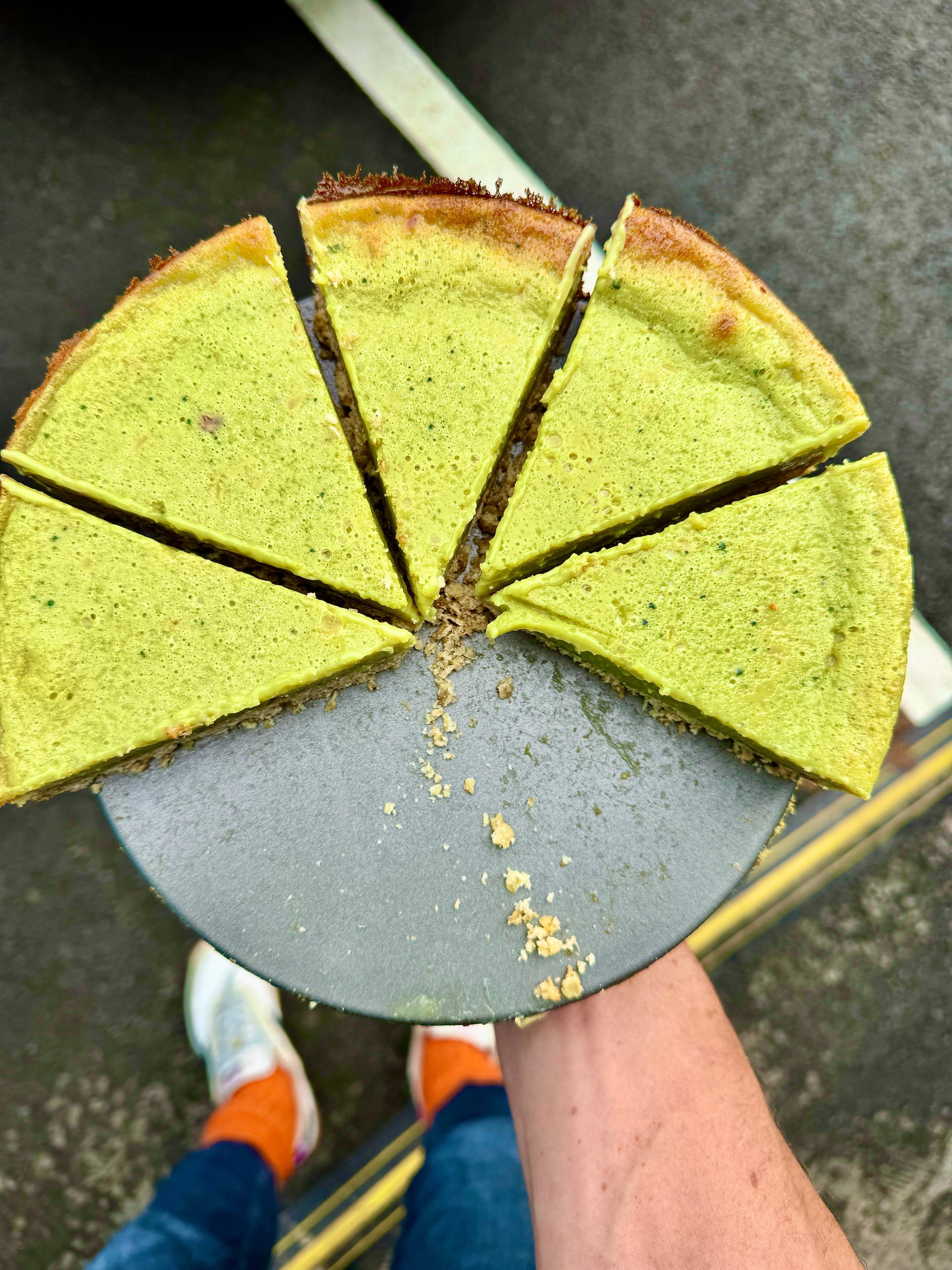green pie being held by a man in orange socks