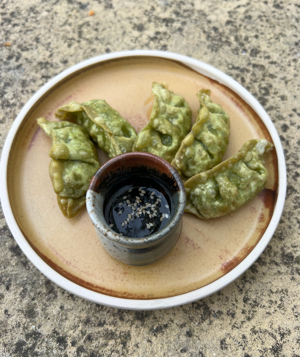 green gyoza dumplings with soy sauce on a plate 